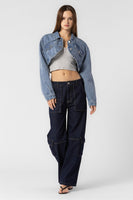 “Beige Botany asymmetrical cropped denim jacket in medium denim wash. Style Number A2450J A stylish, contemporary jacket with an asymmetrical design, crafted in a versatile medium denim wash. The cropped length pairs well with high rise bottoms and a fitted top, creating a fashionable and confident ensemble.”
