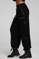 A pair of Chaser Billy Shadow Black Jogger Pants featuring contrast stitching, side cargo pockets, an elastic waist, and deep front pockets. The joggers are shown paired with the matching Cooper Shadow Black Top, creating a stylish and comfortable ensemble. Style Number CW9769-SHDW