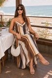 Greylin Clothing Stella Vertical Watercolor Maxi Dress Style G266D7133 in Mustard Brown Neutral Stripe. Woman seated cross-legged in the Stella Watercolor Maxi Dress at a beachside lunch