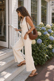Side view of a woman wearing the Raven knit set while walking up the steps of a Hamptons boutique.
