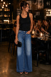 Rails Clothing Dover Palazzo Denim Pant Style 730A-255D-8419 in Boondocks. Woman wearing the Dover Wide Leg Palazzo Jeans with a black ribbed tank top, black strappy heels and a woven blck clutch at an upscale restaurant. Mid-rise drapey denim palazzo jeans with an adjustable tie waist styled for an edgy date night or dinner with friends.