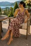 Woman seated on a Hudson Valley stone patio wearing a floral chiffon midi dress styled with clear strap kitten heel sandals, gold jewelry, and a beaded handbag. Rails Clothing Marciana Dress Style 913A-191G-8768 in Cardinal Floral