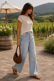 Rails Clothing Cady Top Style 826D-359E-1063 in Stone. A lightweight knit, relaxed denim, and rich cognac accessories create the effortless outfit you'll reach for from brunch to vineyard afternoons. Profile walking view of the Cady lightweight knit top with wide-leg denim at a vineyard.