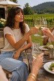 Woman wearing the Cady knit top enjoying lunch and a wine toast with friends at a Hudson Valley vineyard. Rails Clothing Cady Top Style 826D-359E-1063 in Stone. 