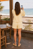 Varley Davidson Sweat Style VAR01080 ANIF in Anise Flower Paired with the Atrium igh Rise Short 4.5. Back view of the Davidson Sweat styled with matching shorts while photographing the ocean