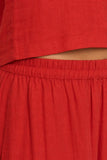 Close-up of the warm red washed linen-blend fabric, elastic waistband and soft natural texture of the Scout Linen Pant